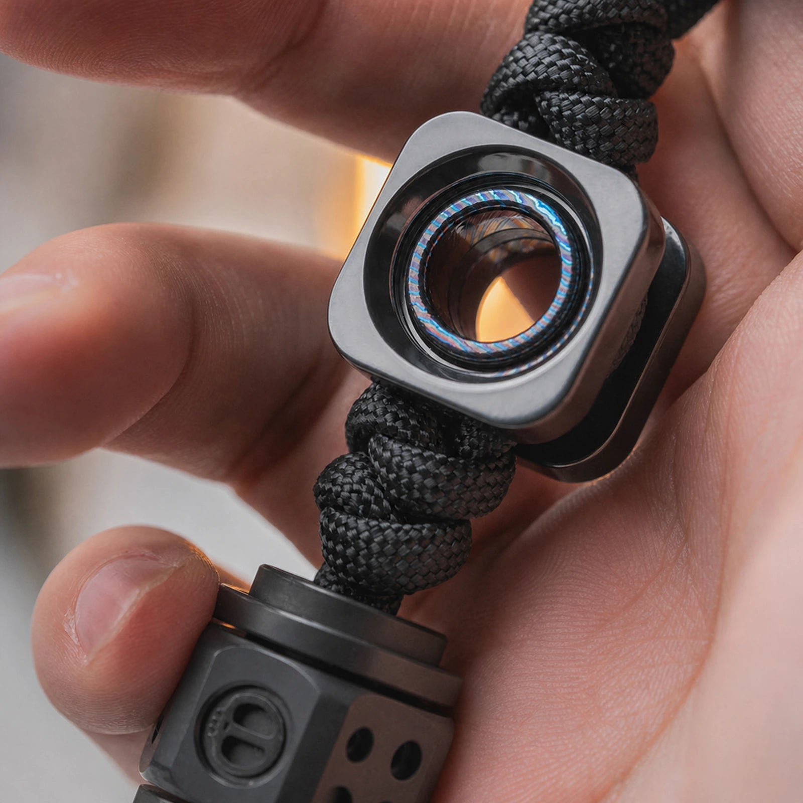 Square EDC lanyard bead with layered circular center held in one hand
