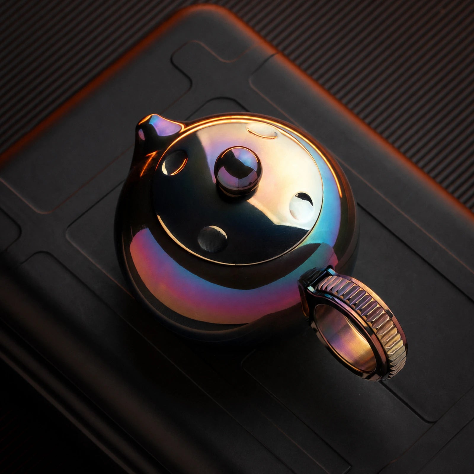 Heat-colored ratchet fidget toy with toothed ring handle in top view