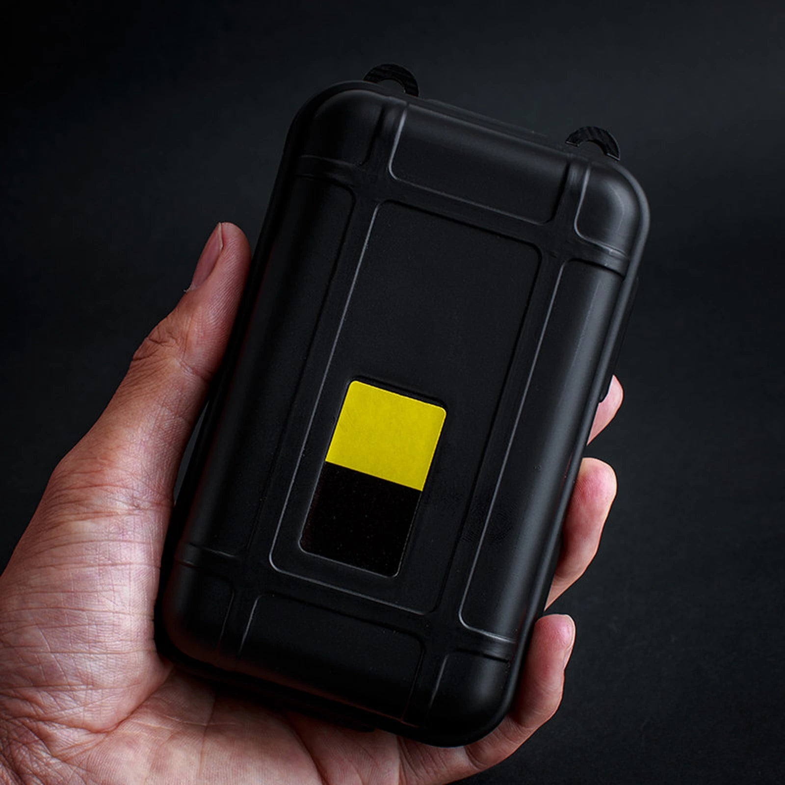 Compact black hard-shell fidget toy storage case held in one hand