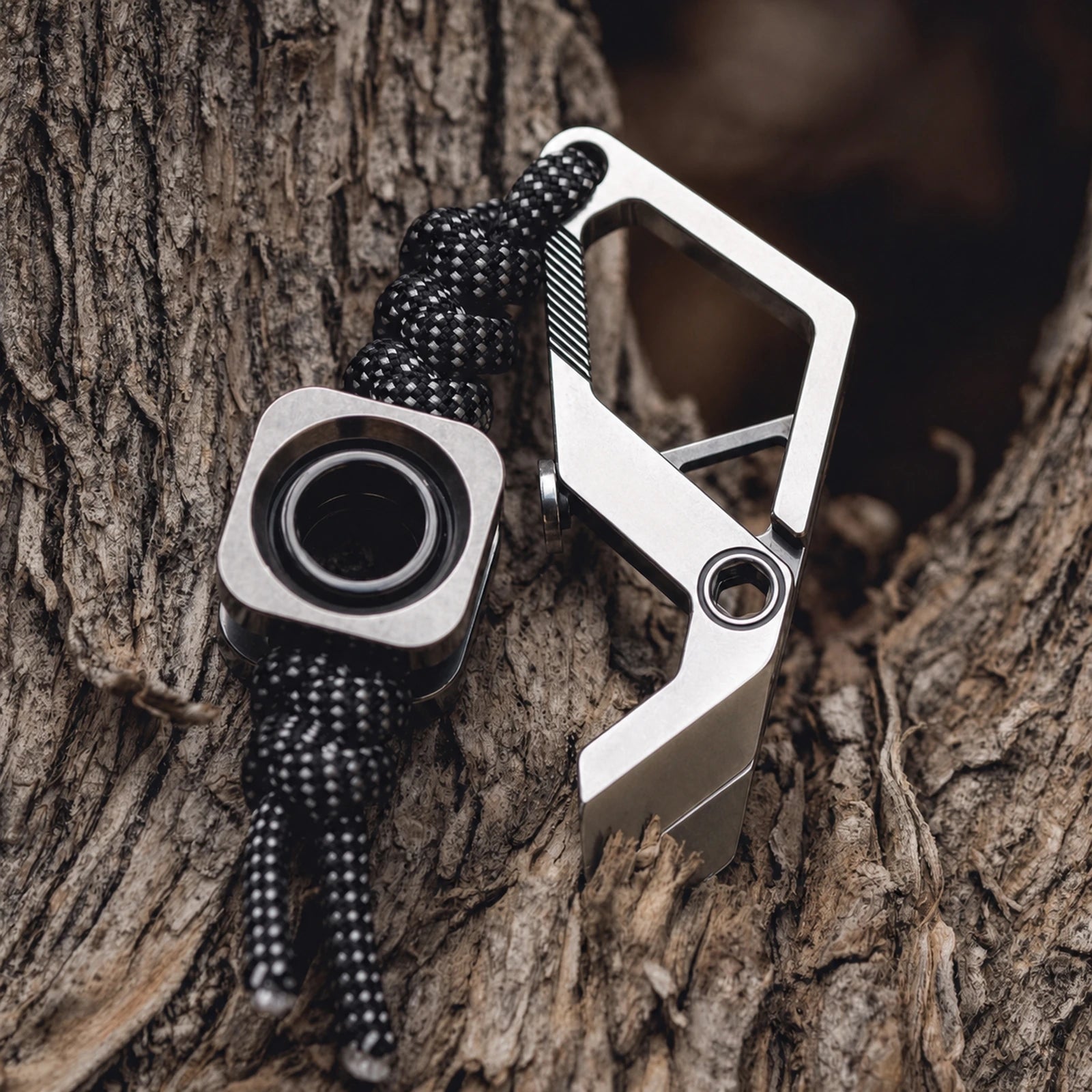 Square metal lanyard bead threaded on black paracord beside a clip