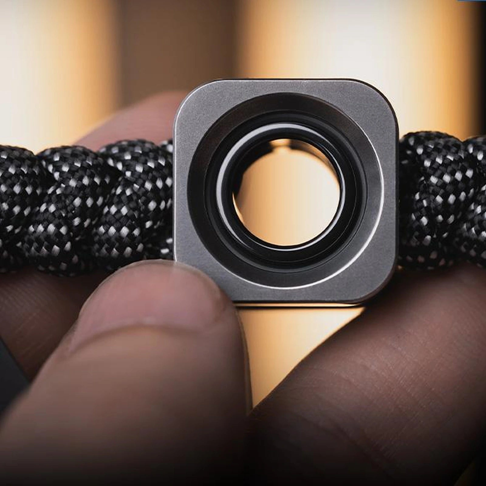 Black square EDC pendant bead with circular center shown between fingers