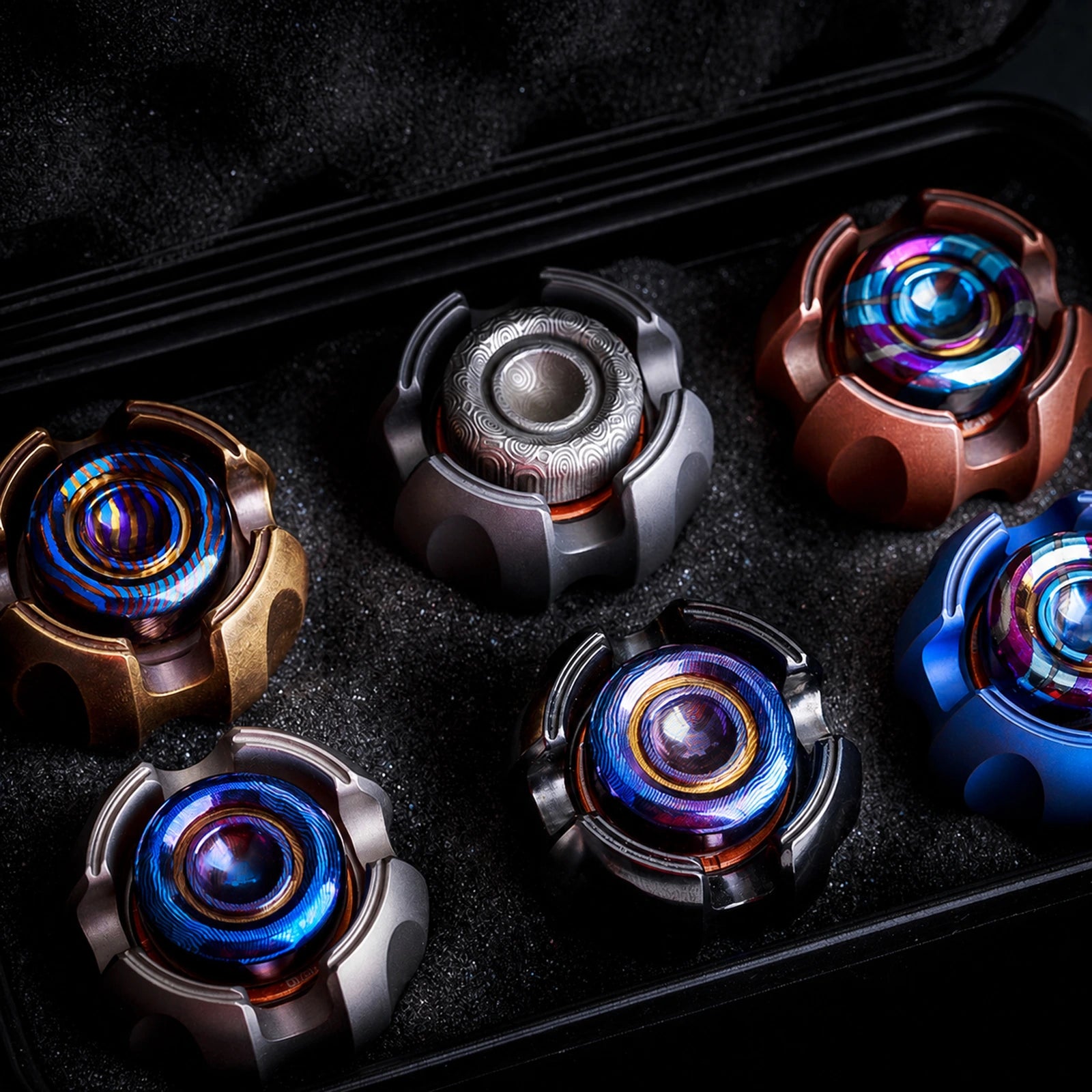 Open foam-lined storage case holding a collection of metal fidget toys