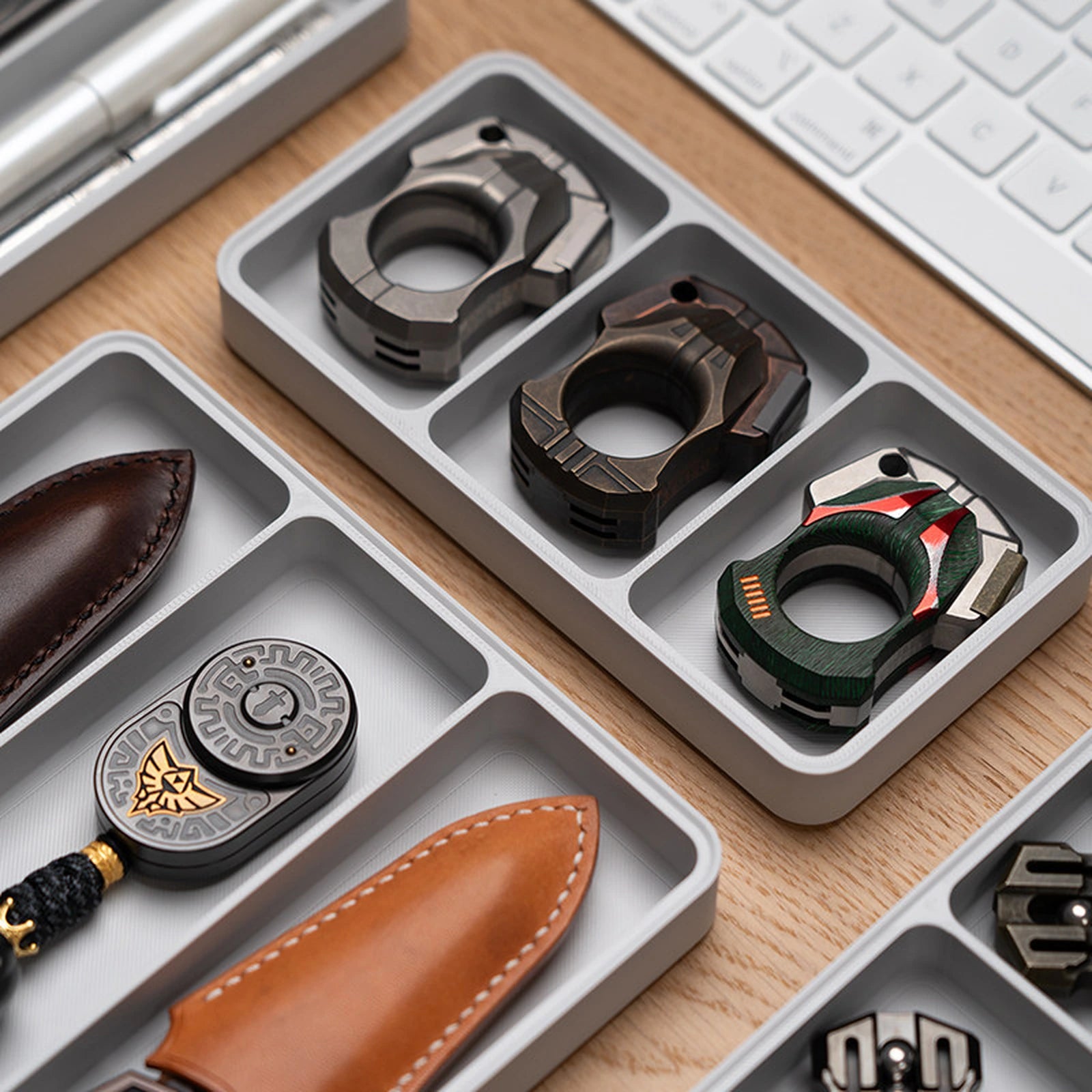 Gray compartment trays arranging rings and compact EDC pieces on a desk